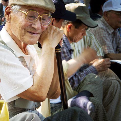 Ältere Männer sitzen entspannt, gestützt auf ihrem Gestock, einer lächelt