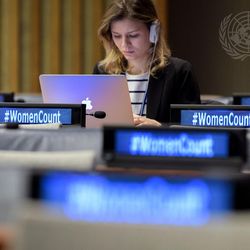 Eine Frau sitzt an einem Laptop und arbeitet, auf den digitalen Anzeigeschildern vor ihr steht #WomenCount