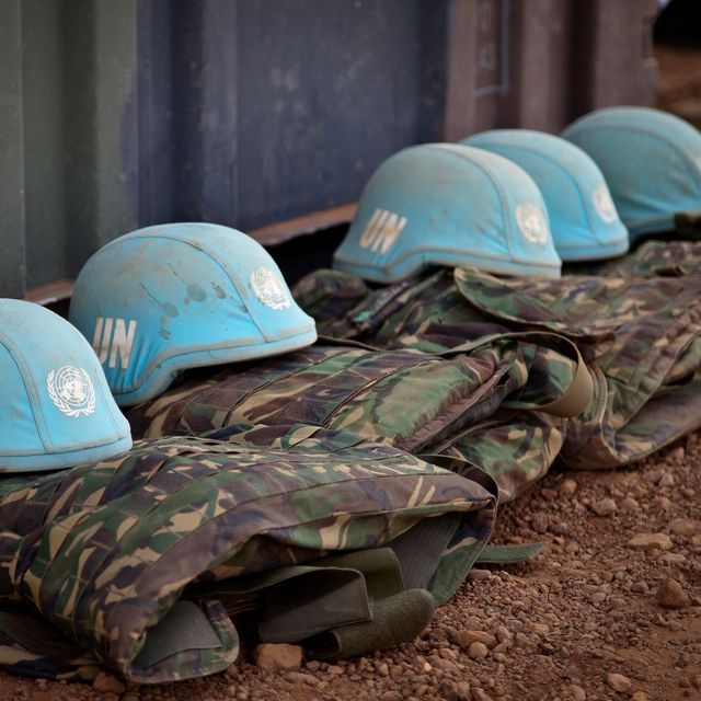 Blaue Helme liegen nebeneinander auf Militärwesten auf dem Boden