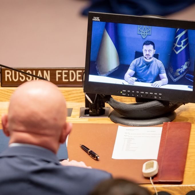 Der russische Botschafter bei den UN schaut auf einen Bildschirm, auf dem ukrainische Präsident zu sehen ist.