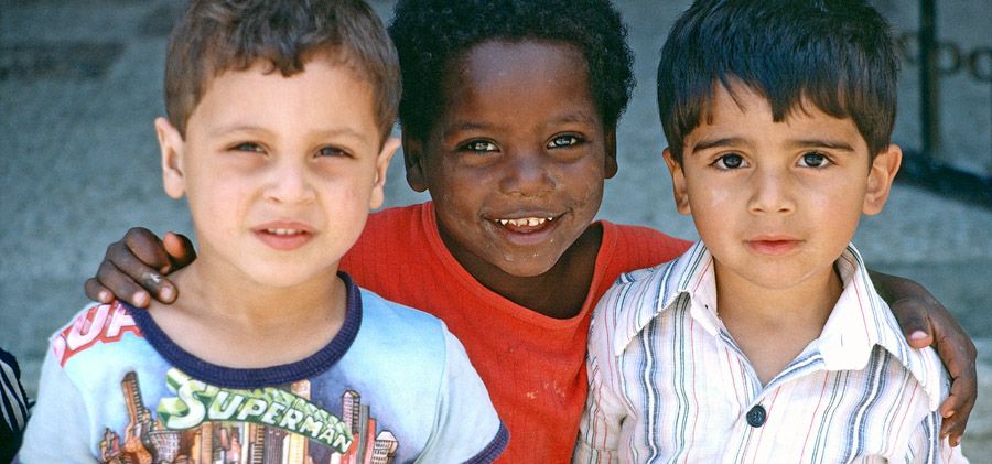 Drei kleine Jungen mit unterschiedlicher Hautfarbe umarmen sich.