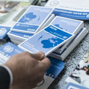 Eine Hand greift ein Exemplar der Charta der Vereinten Nationen von einem Büchertisch.