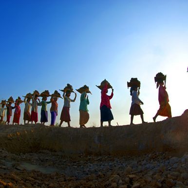 Eine Gruppe von Frauen des Globalen Südens trägt Gegenstände auf ihren Köpfen.