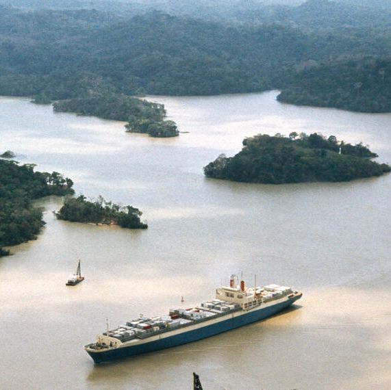 Ein Dampfer im Panamakanal Eine Luftaufnahme eines breiten Kanals, in dem sich ein großer Dampfer befindet