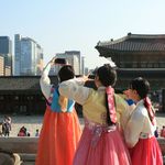Drei asiatische Touristinnen in koreanischen Kostümen machen Selfies im Palast in Seoul