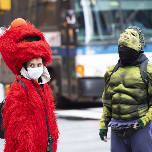 Superhelden mit Einschränkungen: Straßenszene in New York während des COVID-19-Ausbruchs. Elmo trägt eine Maske unter dem Kostüm auf dem Times Square, links ist der Hulk zu sehen.