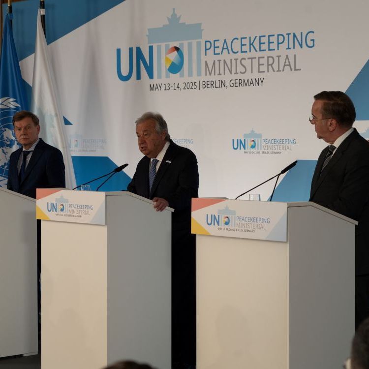 Drei Männer stehen an drei Redepulten vor einem Banner