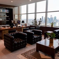 Blick ins Büro mit Ledersesseln, Bücherregal und Fensterfront mit Sicht auf die Skyline von Queens.