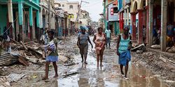 Frauen laufen durch eine vom Hurrikan verwüsteten schlammigen Straße in Haiti.