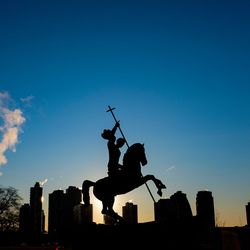 Die Plastik ›Gut besiegt Böse‹ vor der Skyline von Queens zum Sonnenaufgang.